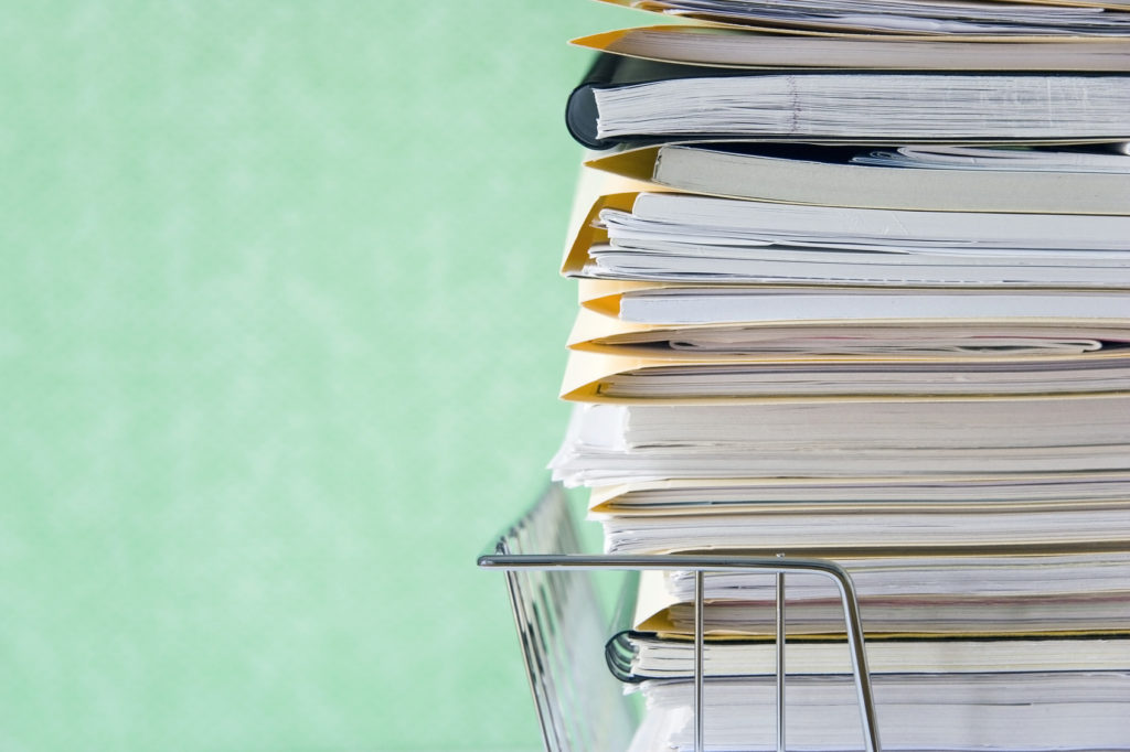 A stack of paper and files in a wire basket